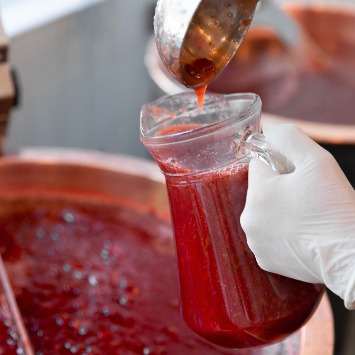 Confiture versée à la louche depuis un chaudron de cuivre pendant l'atelier
