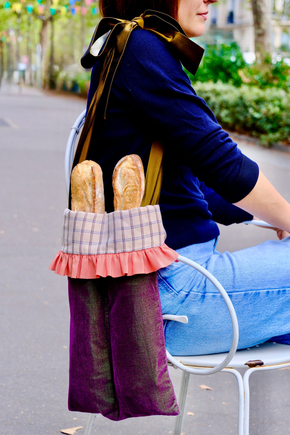 Femme assise en terrasse portant à l'épaule le Tote Bag'ette du calendrier de l'Avent garni de baguettes