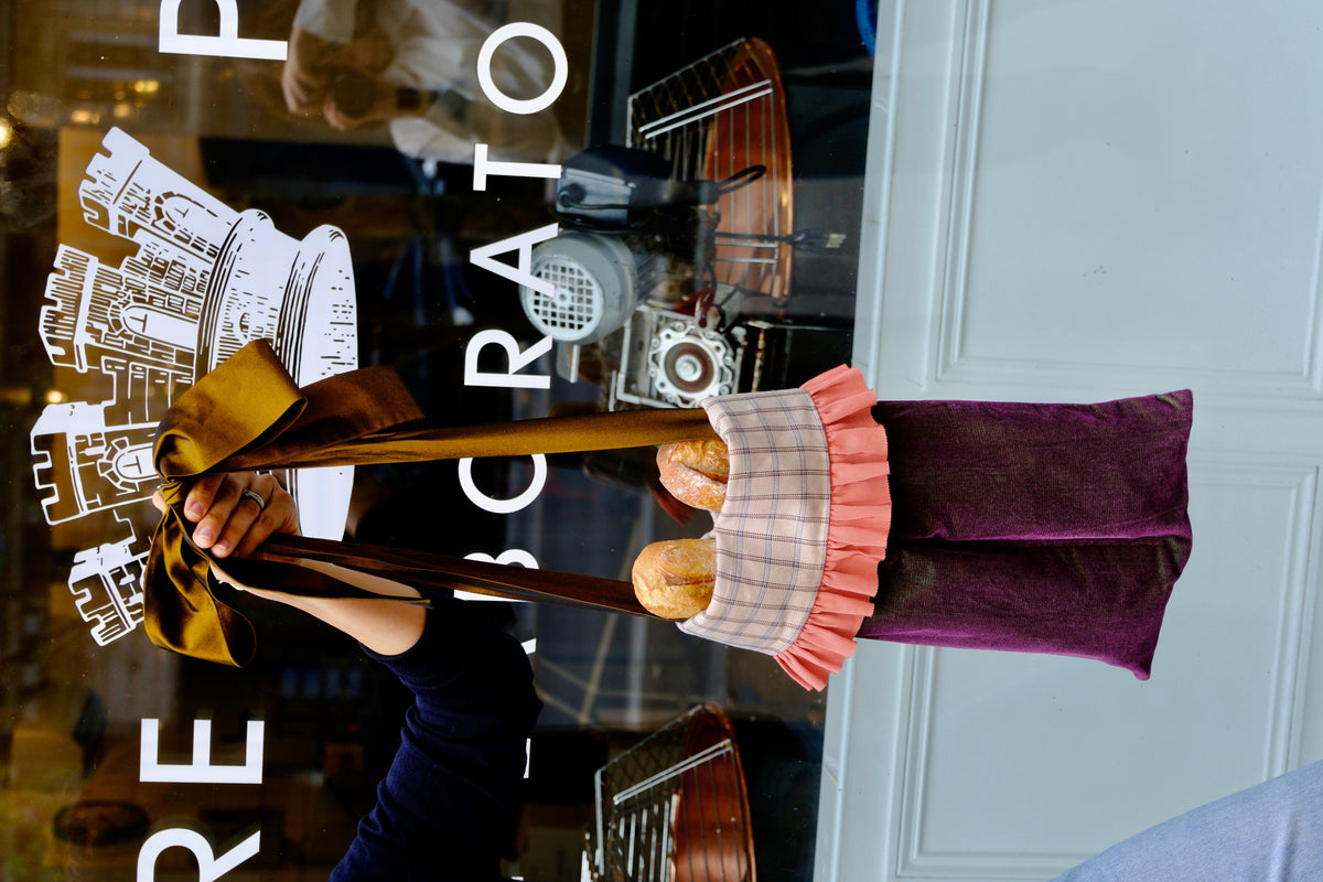 Tote Bag'ette du calendrier de l'Avent tenu devant la vitrine du laboratoire Confiture Parisienne