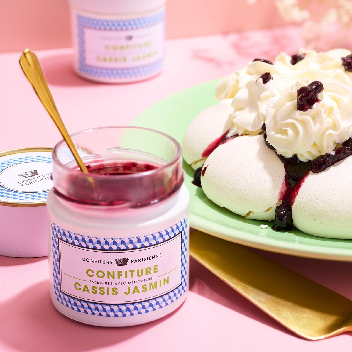 Pot Cassis Jasmin ouvert avec une cuillère dorée près d'une pavlova à la chantilly et aux myrtilles