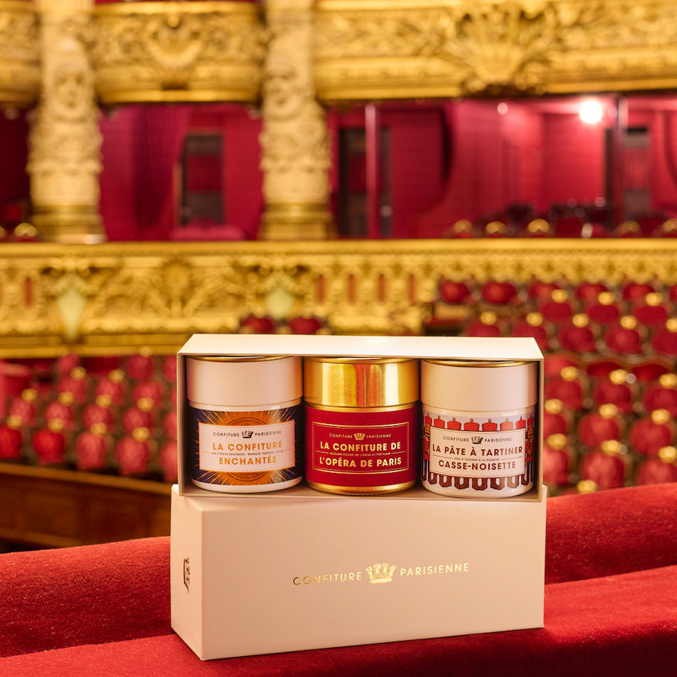 Coffret Collection Opéra de Paris avec trois pots posé sur un fauteuil rouge dans la salle du Palais Garnier