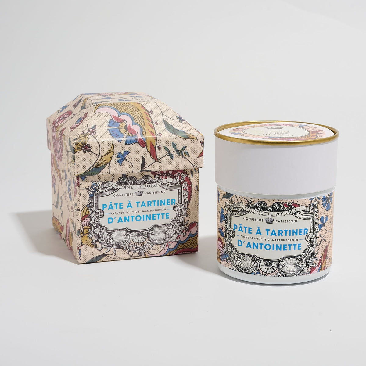 Coffret fleuri et pot de Pâte à Tartiner d'Antoinette x Antoinette Poisson côte à côte sur fond gris clair