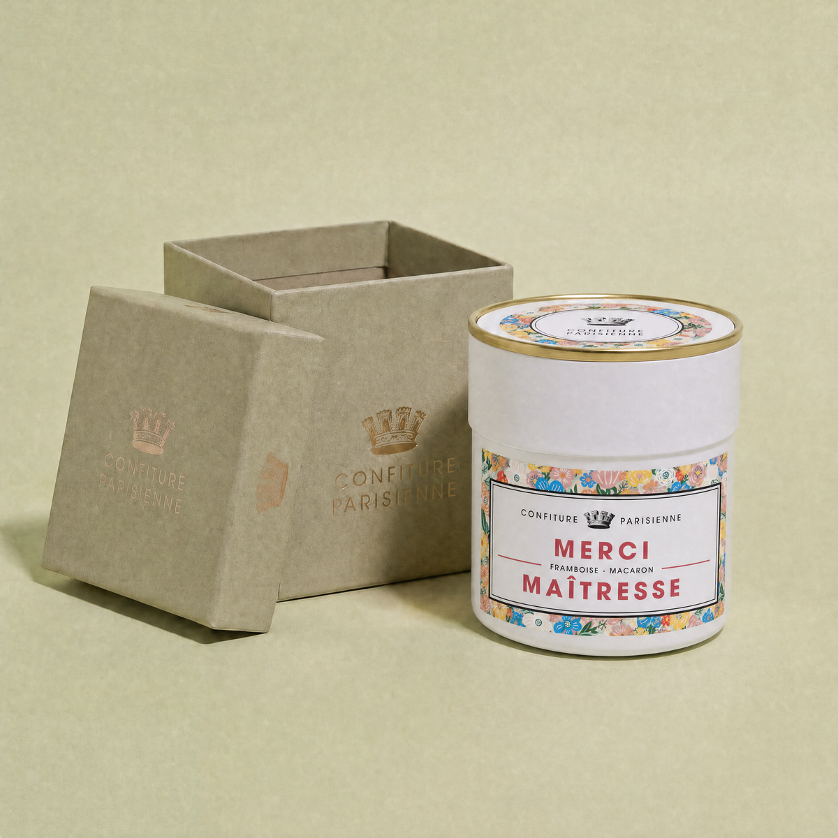 Pot Merci Maîtresse posé devant son écrin kraft ouvert au logo Confiture Parisienne, sur fond vert sauge