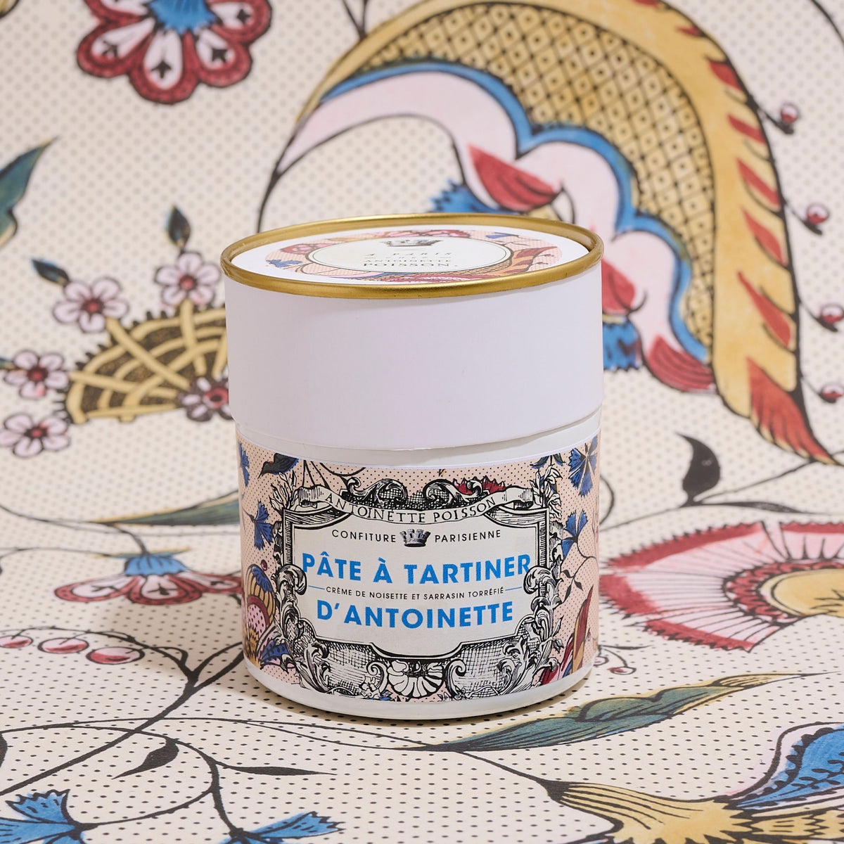 Pot de Pâte à Tartiner d'Antoinette x À Paris chez Antoinette Poisson devant un papier peint à grandes fleurs