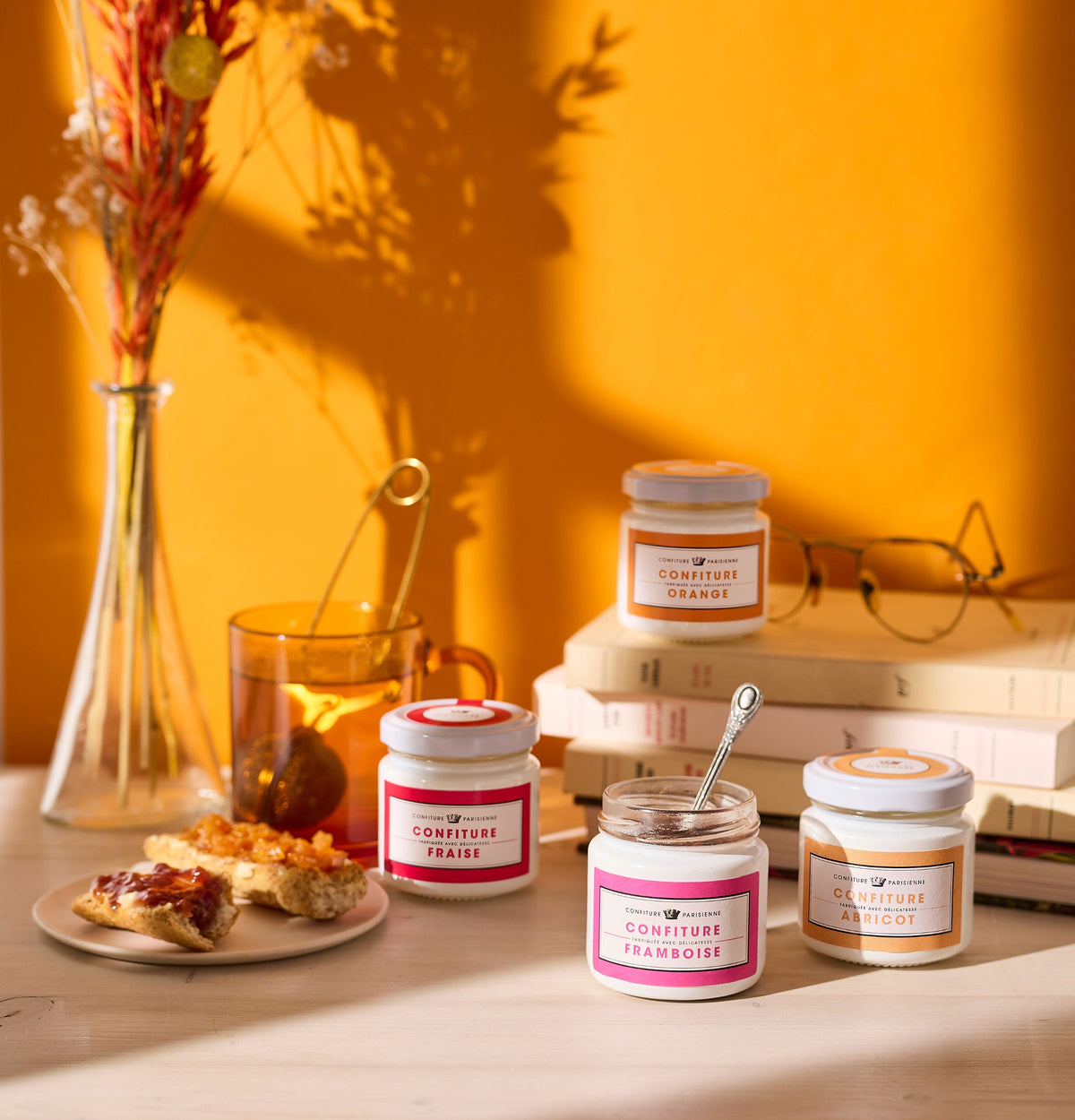 Petits pots de 100 g Orange, Fraise et Framboise sur une table avec livres, tartines et bouquet séché